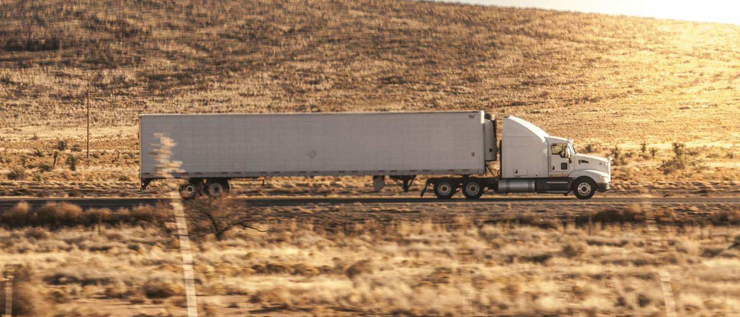 A dry van tractor-trailer running an open highway at golden hour
